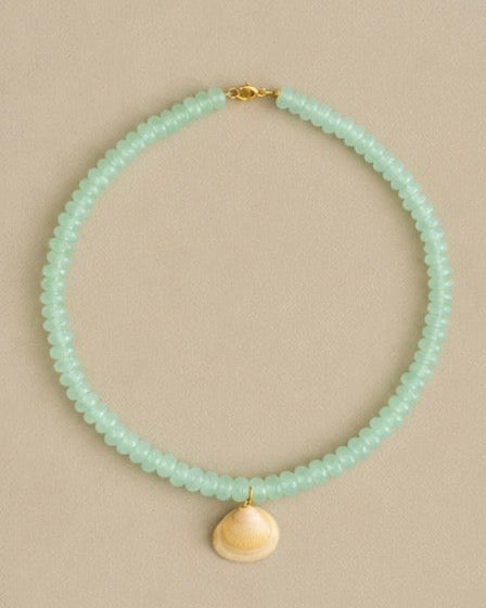 Mint green beaded necklace with a gold clasp on a beige background